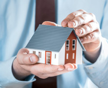 close up of a man holding a tiny model home